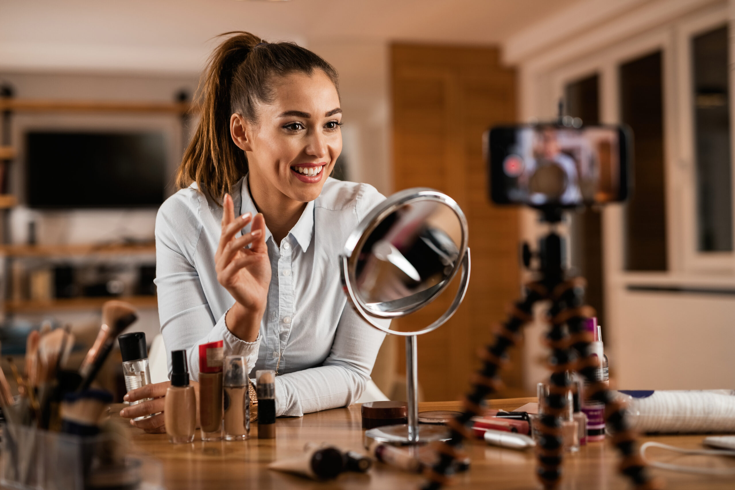 Smiling female influencer talking about beauty products while vlogging from home.